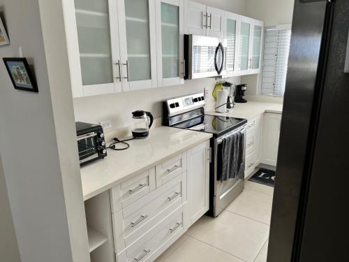 a white kitchen with white cabinets and appliances at Ocho Rios Ocean Escape in Richmond