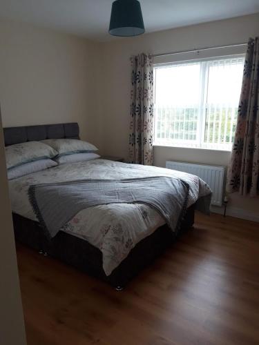 a bedroom with a bed and a large window at 10 Clara Meadows in Culdaff