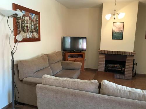 a living room with a couch and a television at Casa Rural las Escuelas II in Hoyo de Pinares