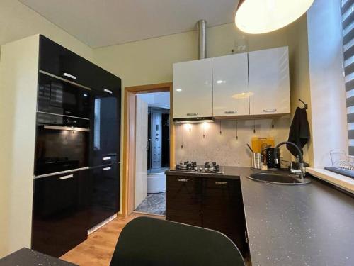 a kitchen with white cabinets and a black counter top at River Apartment Riga in Rīga