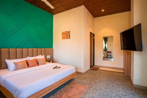 a bedroom with a large bed and a flat screen tv at Zostel Plus Lonavala in Lonavala
