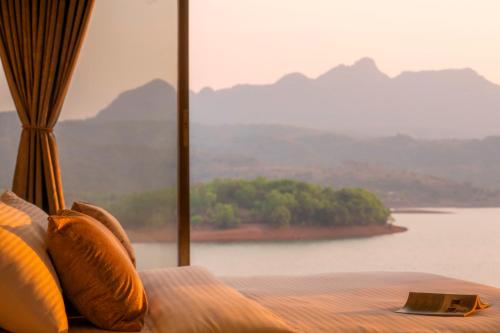 a bed with pillows and a view of a lake at Zostel Plus Lonavala in Lonavala