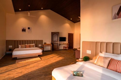 a bedroom with two beds and a room with a television at Zostel Plus Lonavala in Lonavala