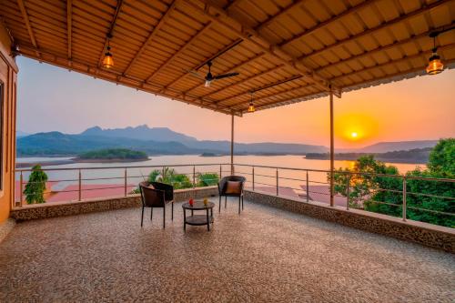 a balcony with chairs and a view of the water at Zostel Plus Lonavala in Lonavala