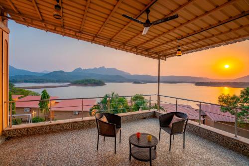 a balcony with two chairs and a view of a lake at Zostel Plus Lonavala in Lonavala
