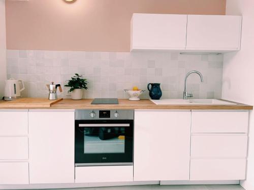 a kitchen with white cabinets and a sink and an oven at Studio d'architecte à 150 m de la plage in Royan