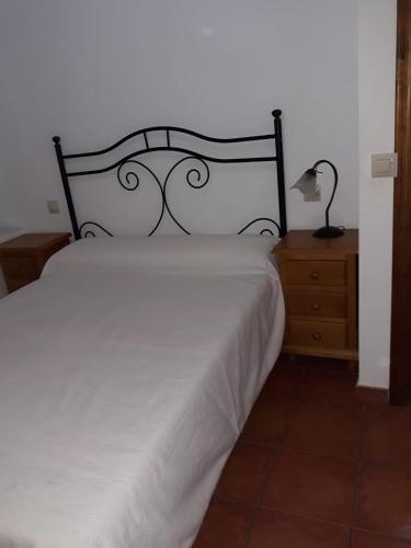 a bedroom with a white bed and a lamp on a dresser at Casa Rural Rio Canto in El Hornillo