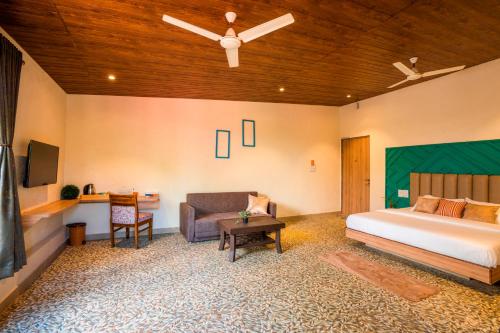 a bedroom with a bed and a couch and a tv at Zostel Plus Lonavala in Lonavala