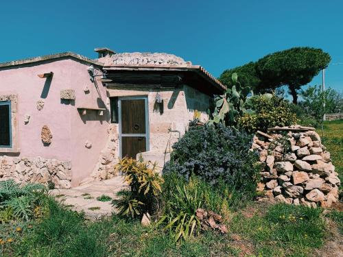 ein kleines rosafarbenes Haus mit einer Tür im Hof in der Unterkunft Trullo Contrada Stracca in Alliste