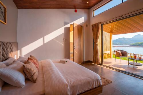 a bedroom with a bed with a view of the water at Zostel Plus Lonavala in Lonavala