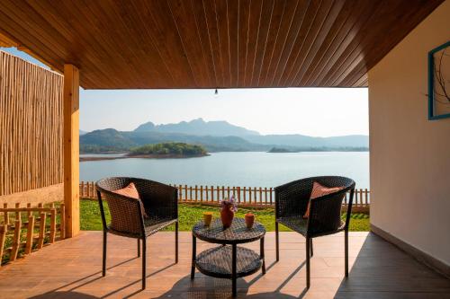 a patio with chairs and a table with a view of a lake at Zostel Plus Lonavala in Lonavala