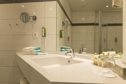 a white bathroom with a sink and a mirror at Aribo Hotel in Erbendorf