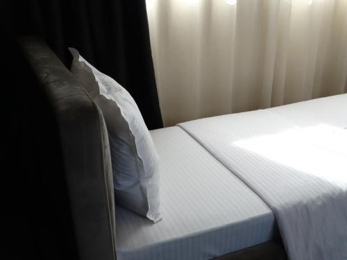 a bed with white sheets and a pillow at Hotel Keto in Podgorica