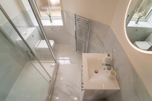 a white bathroom with a sink and a mirror at Foundry Farm Apartment in Hexham