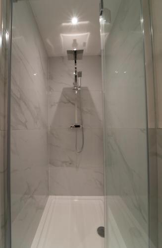 a bathroom with a shower with a glass door at Foundry Farm Apartment in Hexham