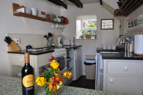 una cocina con una botella de vino y un ramo de flores en Old Cottage, Crackington Haven, North Cornwall, en Bude