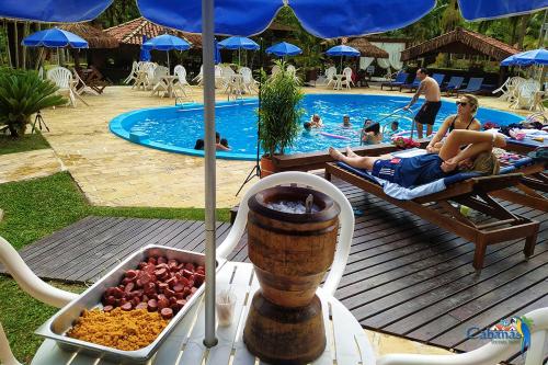 a pool with a table with food and people in the pool at Cabanas Termas Hotel in Gravatal
