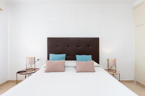 sypialnia z dużym białym łóżkiem z niebieskimi i różowymi poduszkami w obiekcie OLIVIA SUNSET Perfect Stay by Sunkeyrents w mieście Puerto de Santiago