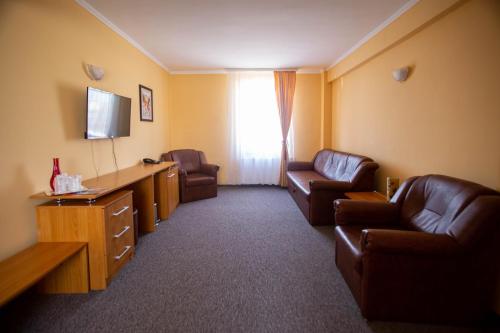 a hotel room with two leather chairs and a television at Hotel Alexandra in Timişoara