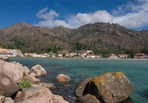 a group of rocks in the water with a mountain at Apartamento Chamela in O Pindo