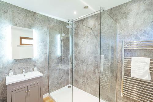 a bathroom with a glass shower and a sink at Kestrel Lodge 6 with Hot Tub in Newton Stewart