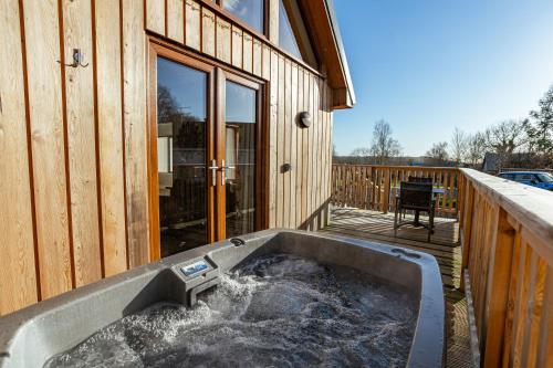 a hot tub on the deck of a house at Kestrel Lodge 6 with Hot Tub in Newton Stewart