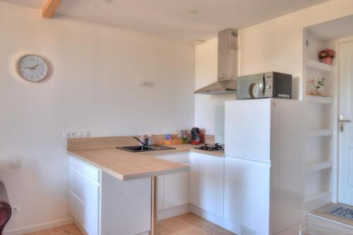 La cuisine blanche est équipée d'un évier et d'un réfrigérateur. dans l'établissement La vie en rose, à Ploubezre