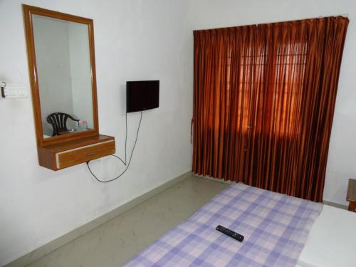 een slaapkamer met een bed en een spiegel bij R M Guest House in Kālapettai