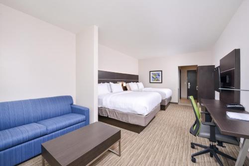 a hotel room with a bed and a blue couch at Holiday Inn Express Donaldsonville by IHG in Donaldsonville