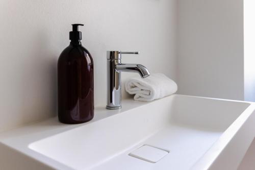 a bottle of soap next to a bathroom sink at Beautiful Apartments on Strøget in Copenhagen City Center in Copenhagen