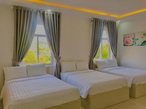 フーコックにあるNguyên Nhân Hotelの窓が2つある部屋にベッドが2つある