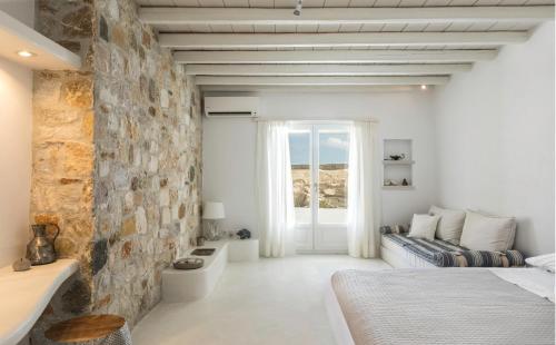 a bedroom with white walls and a stone wall at Villa Conza Mykonos in Agios Ioannis Mykonos