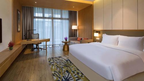a bedroom with a large white bed and a desk at Holiday Inn Kunshan Huaqiao by IHG in Kunshan