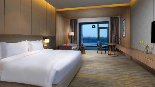 a large white bed in a hotel room with a view at Holiday Inn Kunshan Huaqiao by IHG in Kunshan