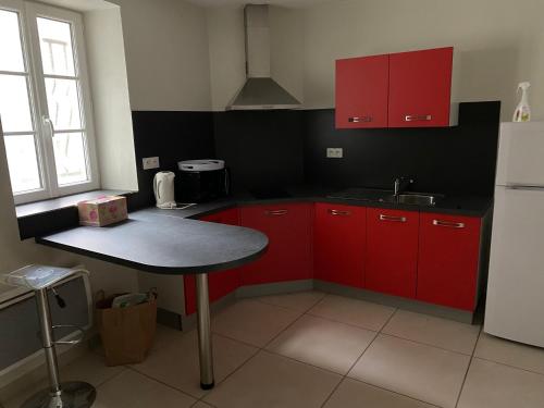- une cuisine avec des placards rouges et une table dans l'établissement Appartement calme centre ville historique, à Ussel