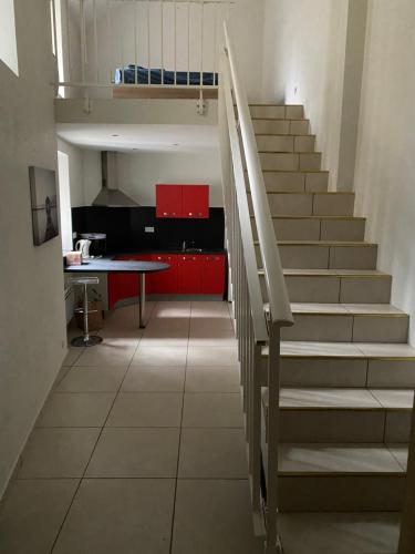un escalier dans une pièce avec une table et des armoires rouges dans l'établissement Appartement calme centre ville historique, à Ussel
