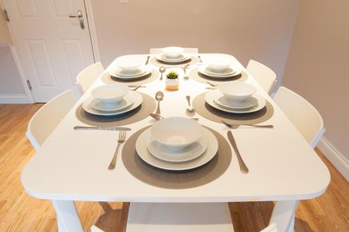a white table with white dishes and spoons on it at Aztec House - Modern & Spacious, 6 separate beds in Derby