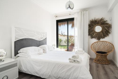 a white bedroom with a large bed and a window at Akivillas Setúbal Paradise in Setúbal