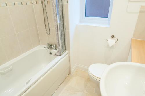 a bathroom with a toilet and a tub and a sink at Aztec House - Modern & Spacious, 6 separate beds in Derby