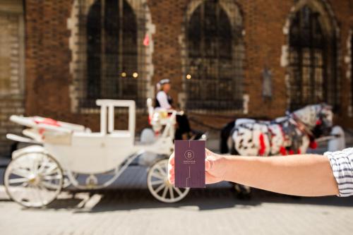 a persons hand holding a passport with a horse drawn carriage at Balthazar Design Hotel in Kraków