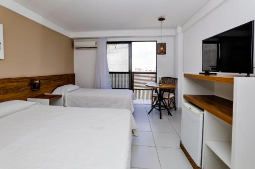 a hotel room with two beds and a television at Porto Suítes Natal Hotel in Natal
