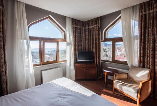 a bedroom with a bed and a chair and windows at Sheki Palace Hotel in Sheki