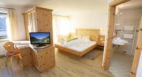 een slaapkamer met een bed en een televisie. bij Hotel Vernagt in Senales