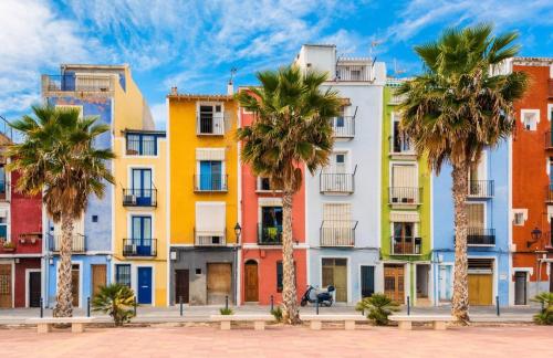 eine Reihe von farbenfrohen Apartmenthäusern mit Palmen in der Unterkunft Apartamento Marinero en Primera Linea in Villajoyosa