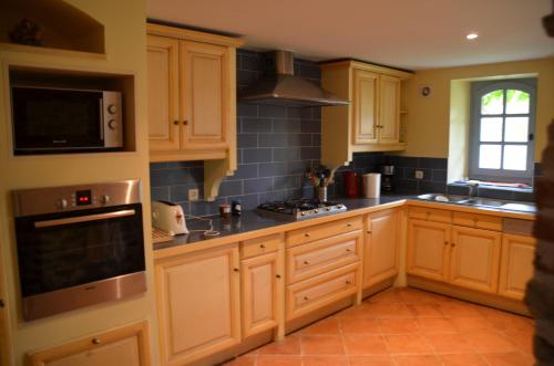 a kitchen with wooden cabinets and a stove top oven at Les Roses d'Autan in Auriac-sur-Vendinelle