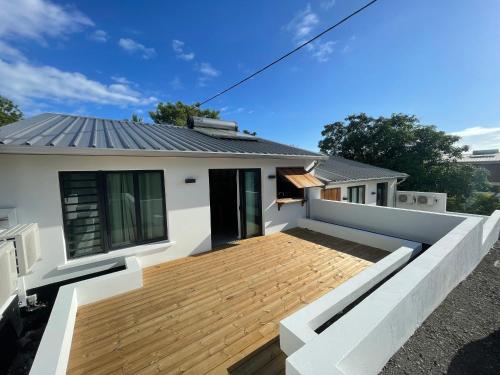 a house with a wooden deck in front of it at Villa Pwintosel 1, calme et confort à 300m de l'océan in Saint-Leu