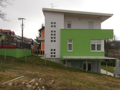 a green and white building next to a field at Apartments Da - Dent in Sveti Ivan Zelina