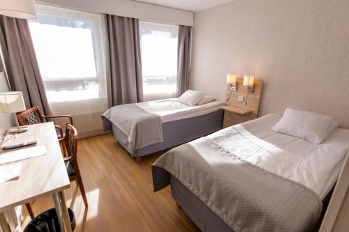 a hotel room with two beds and a desk at Hotel Hirvi in Äänekoski