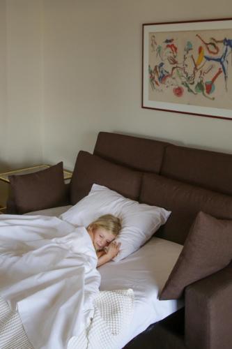 a girl laying on a pillow in a bed at Astoria Hotel Thessaloniki in Thessaloniki