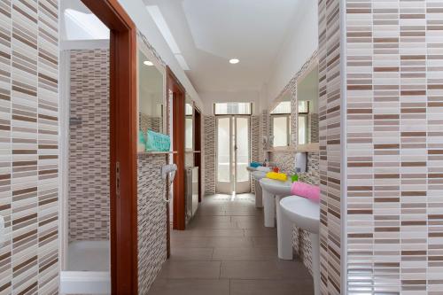 La salle de bains est pourvue de deux lavabos et d'une rangée de miroirs. dans l'établissement Budget Rooms Des Artistes, à Rome